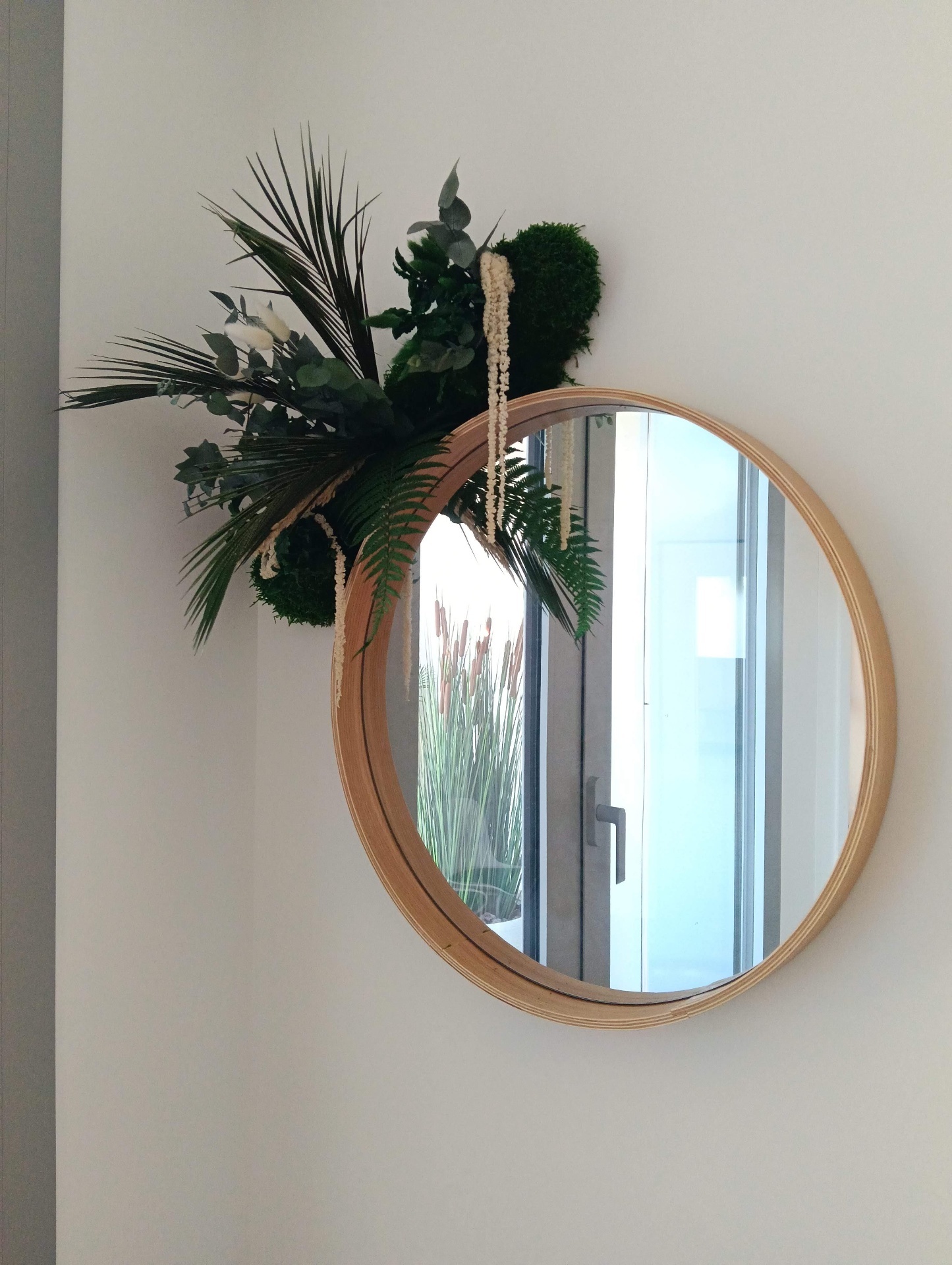 Fixation d'un grand miroir rond cadre bois clair avec décoration végétale — entrée