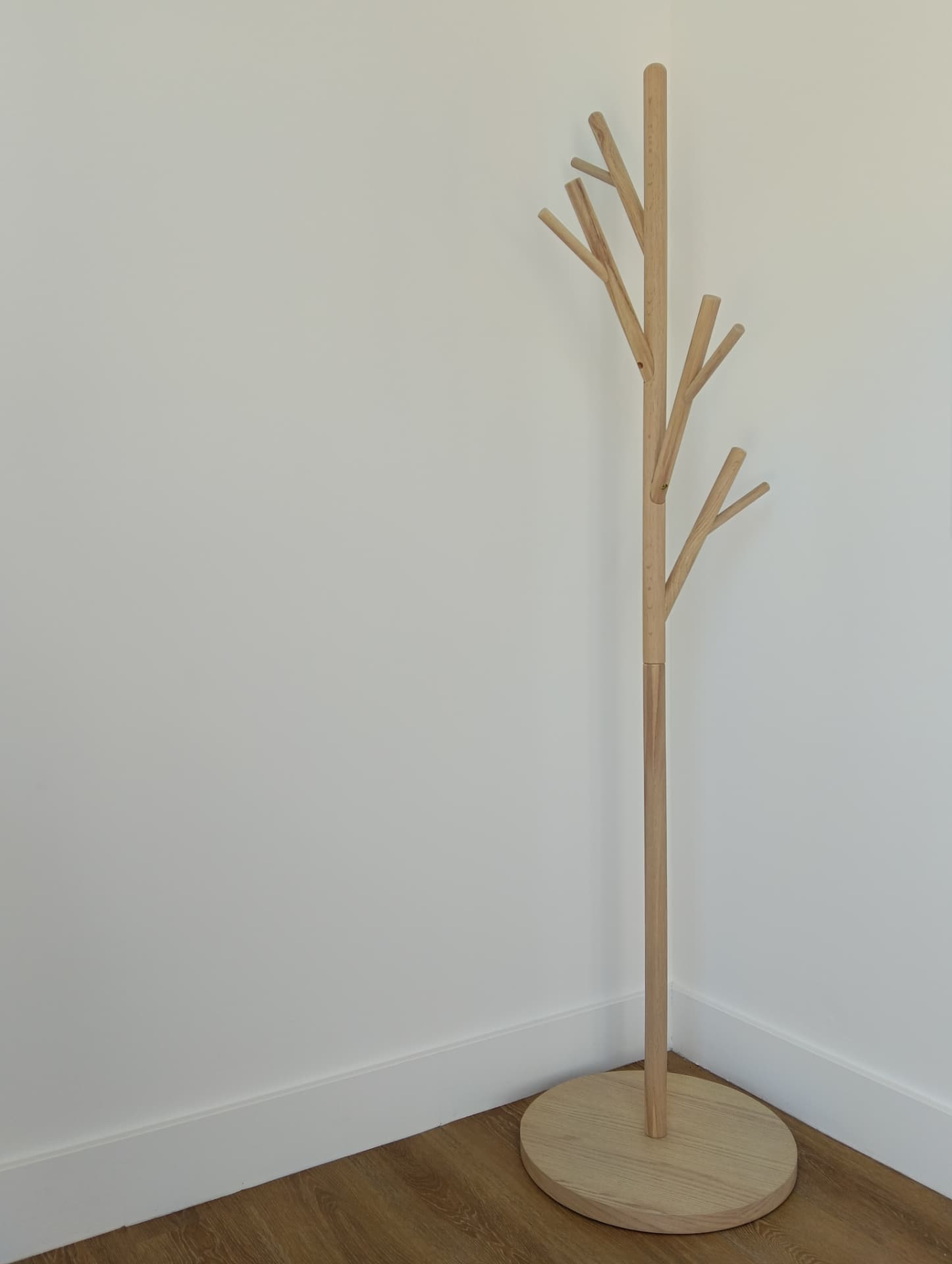 Montage d'un porte-manteau arbre en bois clair pour l'accueil de locaux professionnels à Chambéry